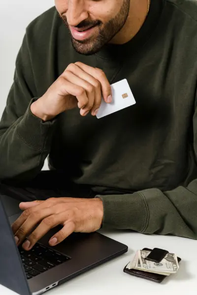a man holding a card, with his wallet on the left side, trying to purchase online