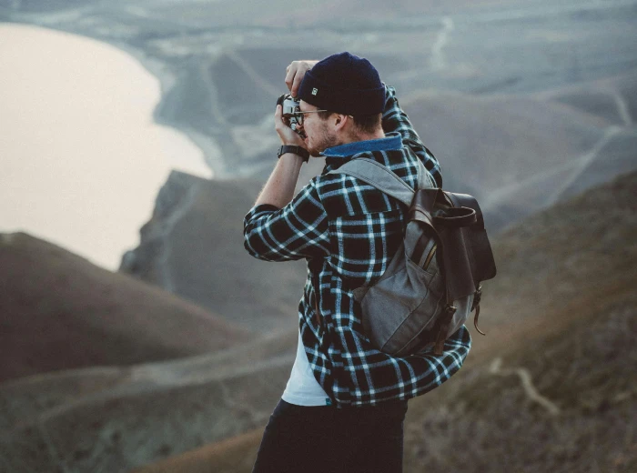 a man doing photography wearing a backpack and a checkered polo